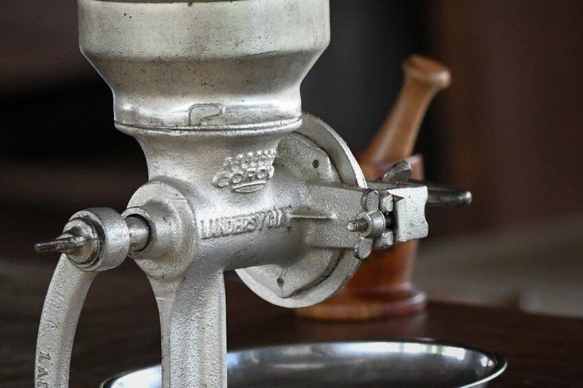 A vintage meat grinder with a metal body and a wooden handle. 2