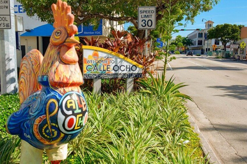 A colorful rooster statue, a speed limit sign, and a welcome sign for Calle Ocho. 2