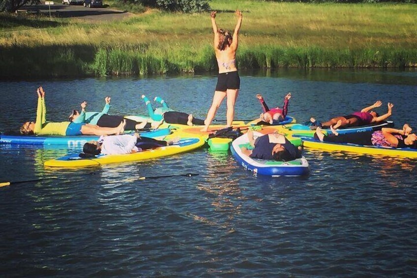 People on paddleboards in a body of water with grassy banks. 2