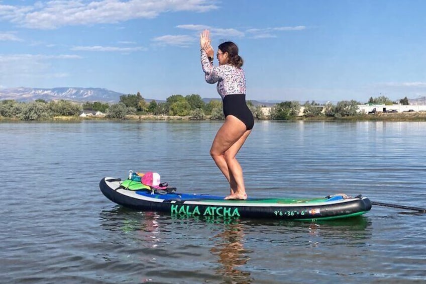 A person standing on a paddleboard in a calm body of water with a mountainous landscape in the background. 4