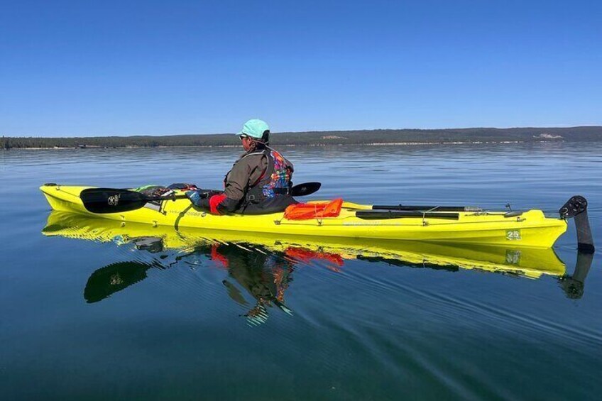 A person in a yellow kayak on calm water with a clear sky. 5