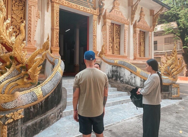 A man and a woman standing at the entrance of a temple with ornate golden dragon sculptures. 2
