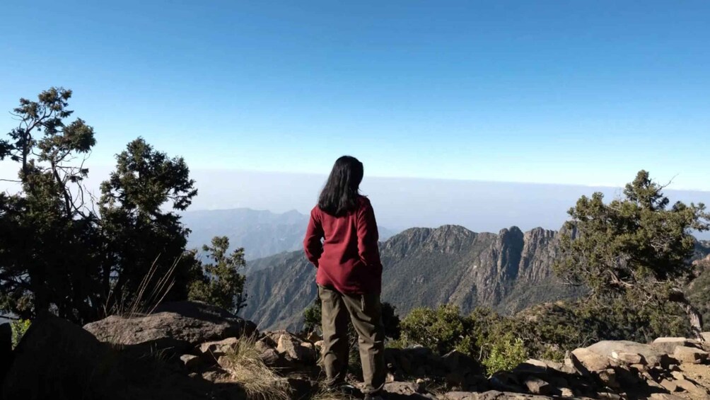A person standing on a rocky outcrop overlooking a mountainous landscape. 3