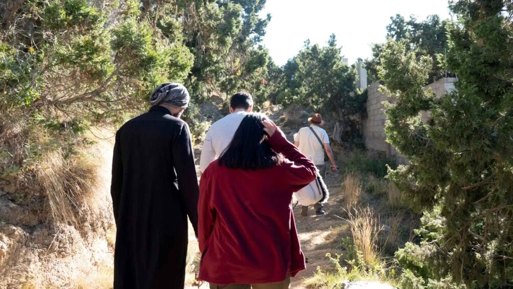 A group of people walking on a narrow path surrounded by trees. 4