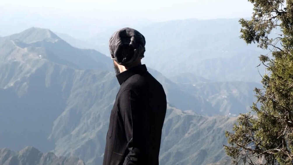 A person standing on a mountain ridge overlooking a range of mountains. 1