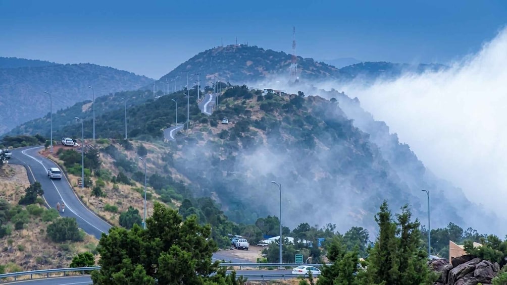 A winding mountain road with vehicles, surrounded by dense forests and hills. 5