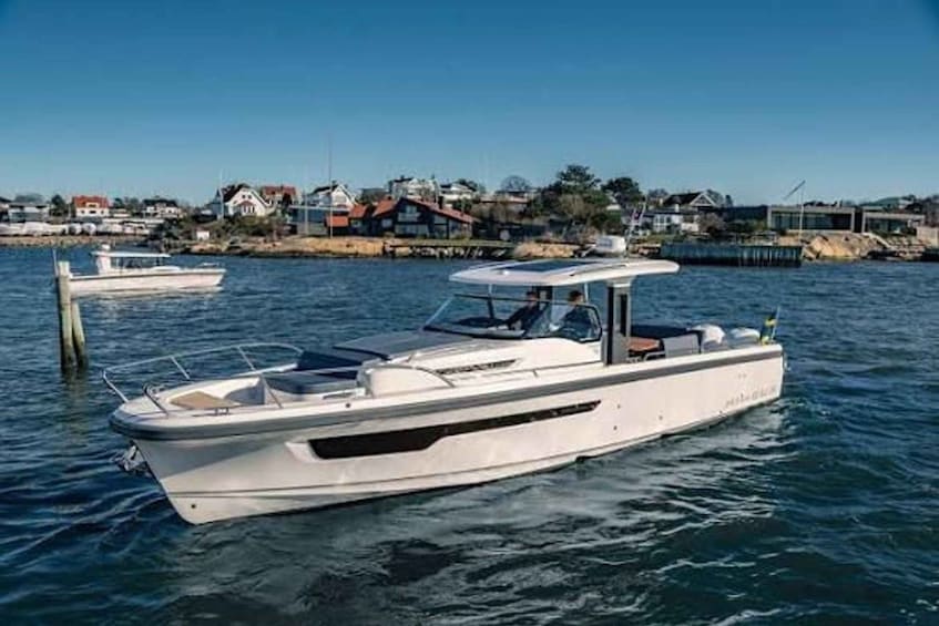 A white motorboat on calm water with a dock in the background and houses along the shore. 5