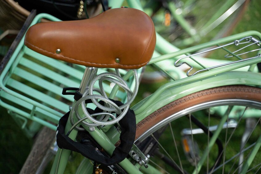 A green bicycle with a brown seat and a black handlebar grip. 4