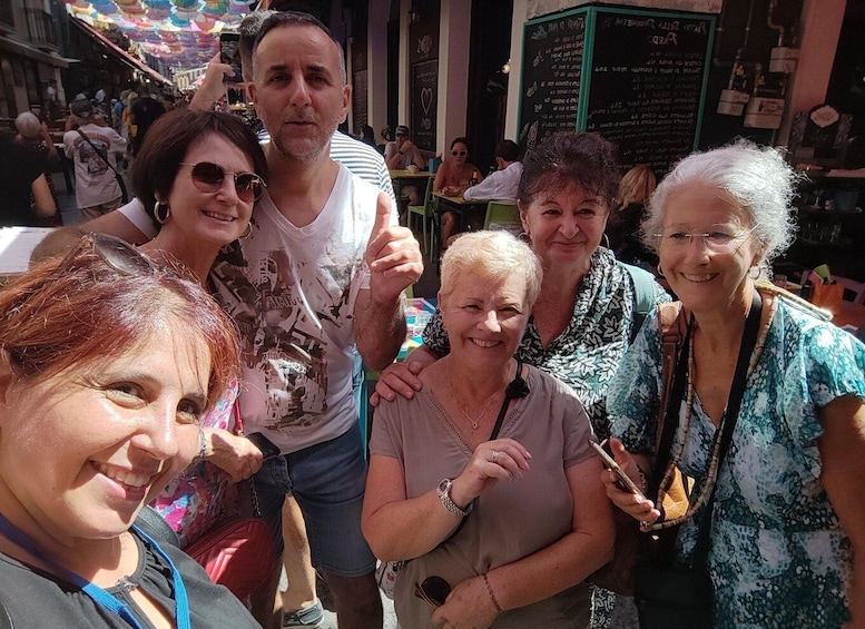 A group of people posing for a photo in an outdoor market area with tables and chairs. 4