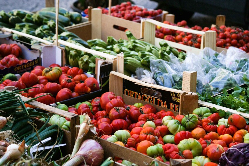 A market stall with various vegetables including tomatoes, cucumbers, and onions. 1