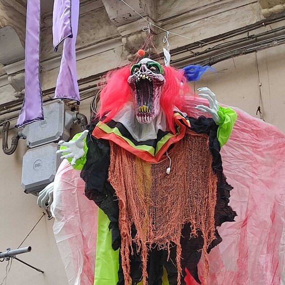 A person in a colorful costume with a skull mask, hanging from a hook. 2