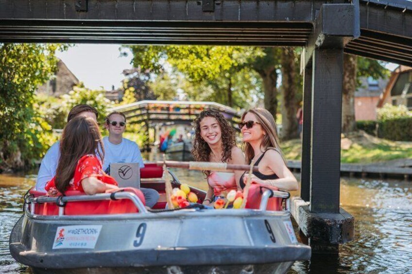 A group of people on a boat with a number 9 sign, a bridge in the background, and greenery around. 5