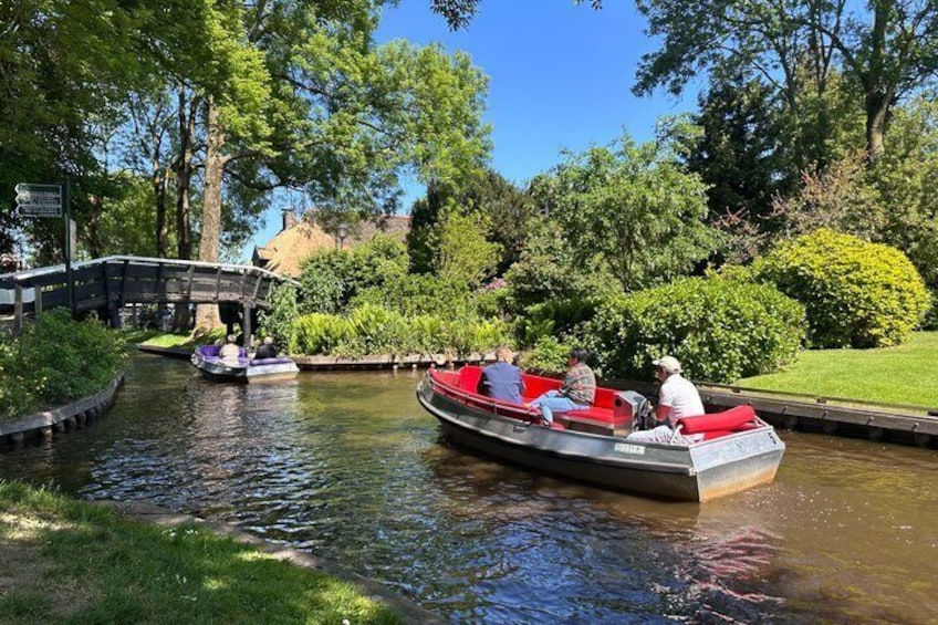 A narrow canal with boats, a wooden bridge, and lush greenery. 5