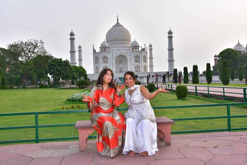 Two people sitting on a bench with the Taj Mahal in the background. 5
