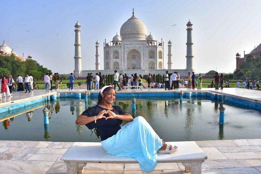 A person sitting by a pool with the Taj Mahal in the background. 2