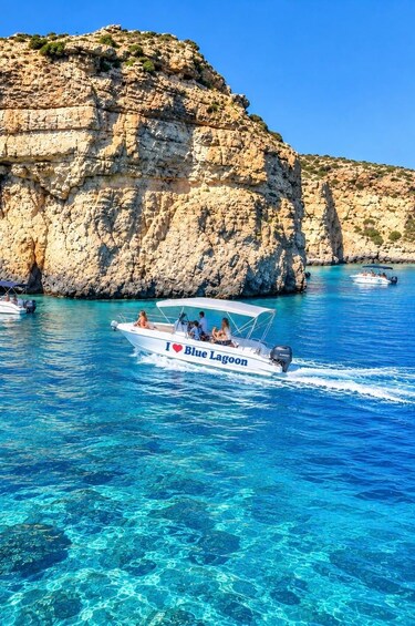 Una barca chiamata 'I ♥ Blue Lagoon' su acque blu cristalline, con scogliere rocciose sullo sfondo. 1