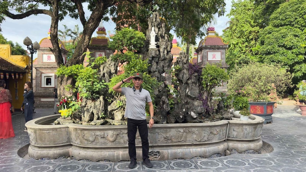 A man standing in front of a rock garden with a traditional building in the background. 3