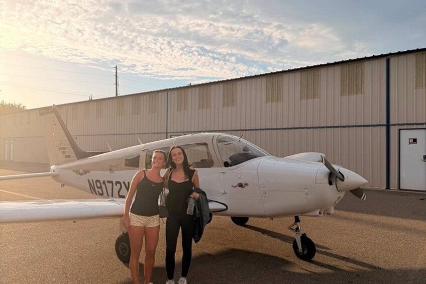 Two people standing in front of a small white airplane with the registration N9172Y. 2