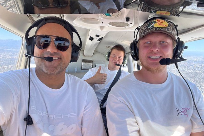 Two people in a cockpit with a cityscape in the background. 1