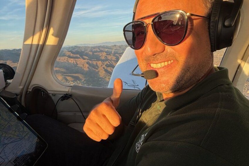 A person in a helicopter cockpit with a view of a mountainous landscape. 3