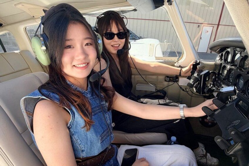 Two individuals in a cockpit, one operating the controls and the other seated. 4