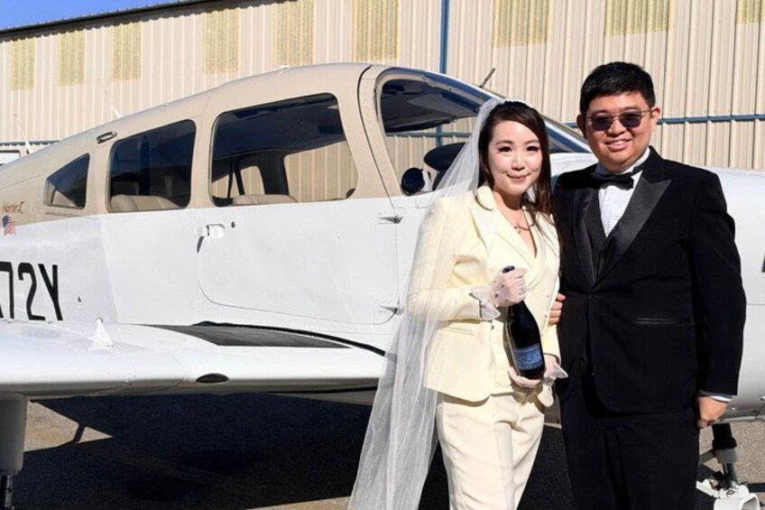 A couple standing in front of a small white aircraft with the registration number 72Y. 2