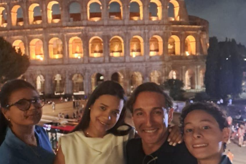 A group of people in front of the Colosseum at night. 2