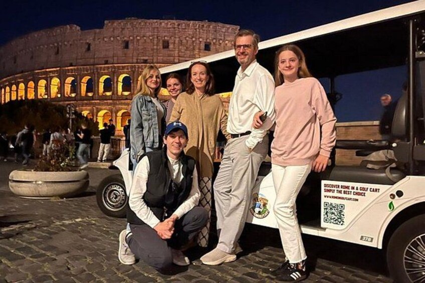 A group of people posing in front of a golf cart with a QR code and a sign that reads 'DISCOVER SOME IN A GOLF CART.' 1