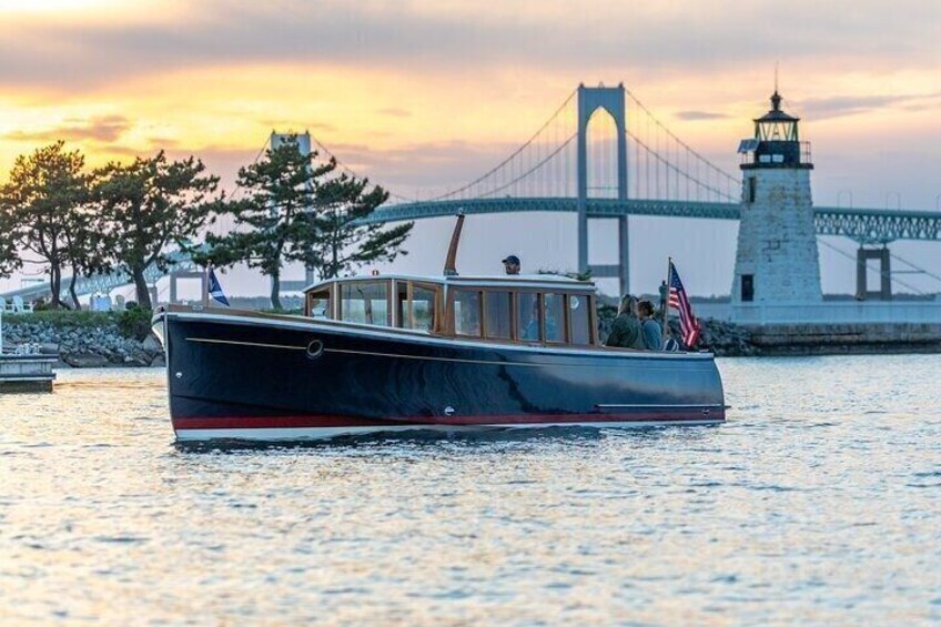 A boat with passengers, a bridge, and a lighthouse in the background. 1