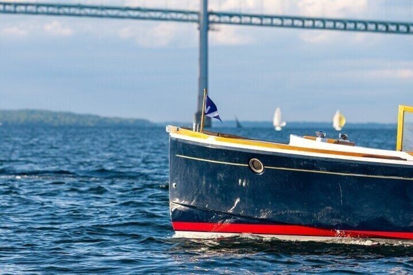 A boat with a red stripe on the hull, a blue flag, and a bridge in the background. 4