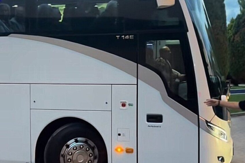 A large white bus with the model number T 145E, a visible door handle, and a wheel. 1