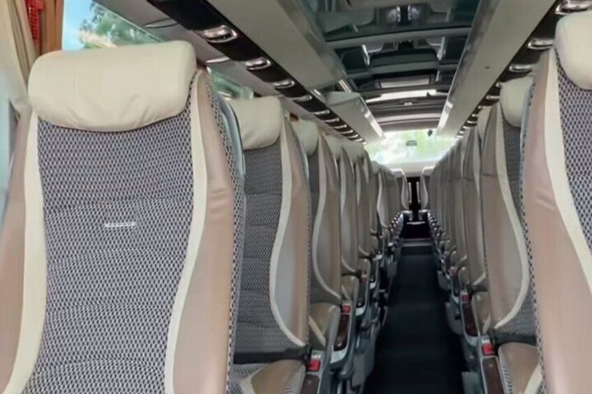 A train interior with rows of seats, overhead compartments, and a central aisle. 3