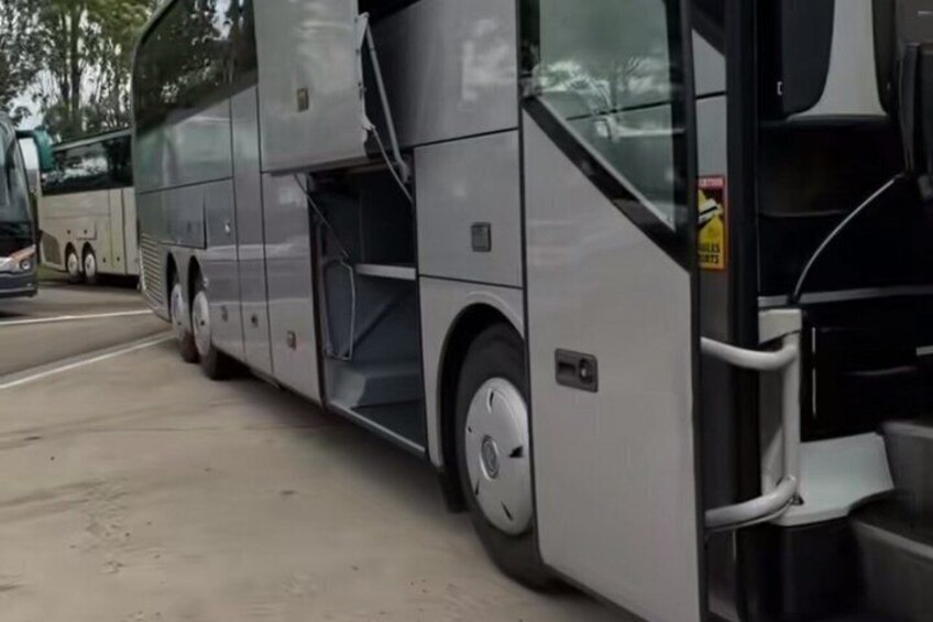 A large bus with a side door open, parked on a road. 2