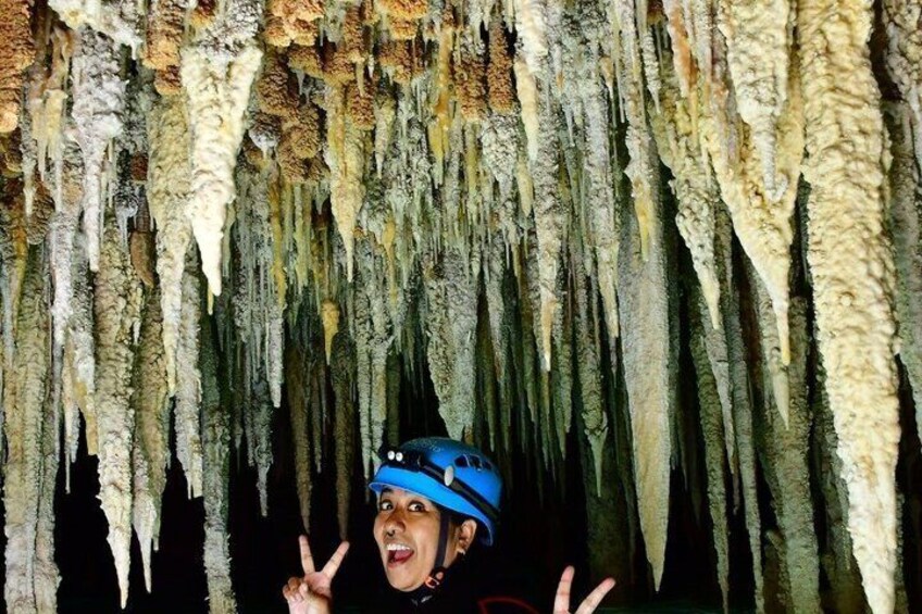 A person in a blue helmet inside a cave with stalactites hanging from the ceiling. 4