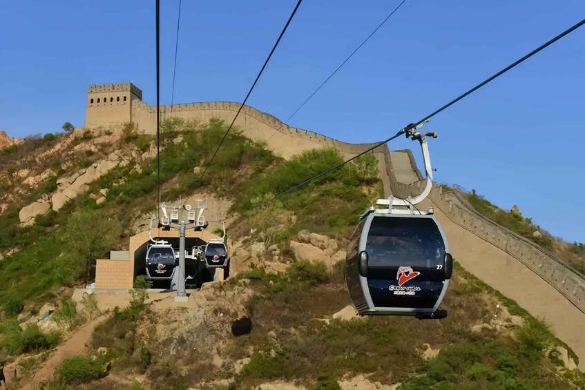 A cable car system with vehicles ascending a steep, rocky hillside. 4
