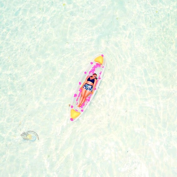 A person lying on a transparent inflatable raft in clear shallow water. 2