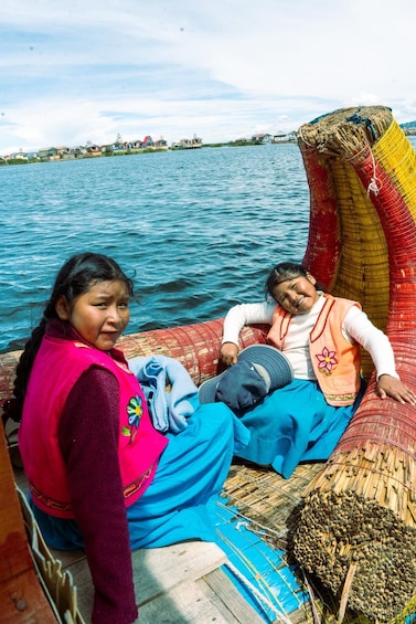 Two people on a boat with a woven basket and a blue tarp. 1