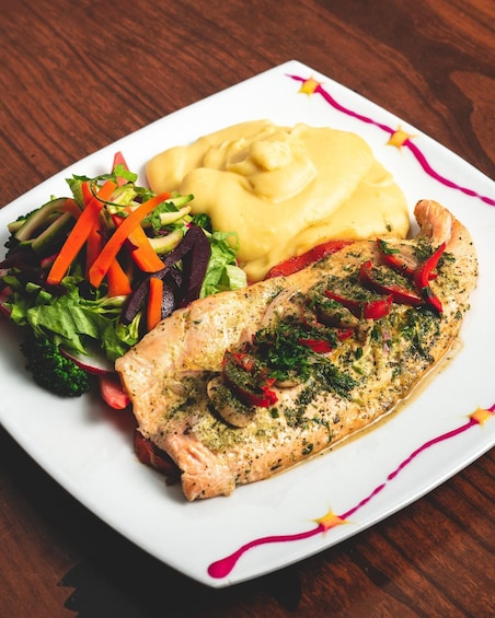 A plate with salmon, mashed potatoes, and a mixed green salad. 5