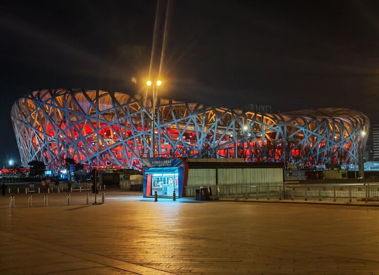 A large, illuminated stadium with a distinctive geometric roof structure. 3