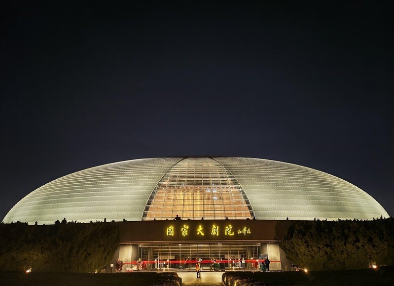 A large, illuminated stadium with a curved roof and a sign in a foreign language. 4