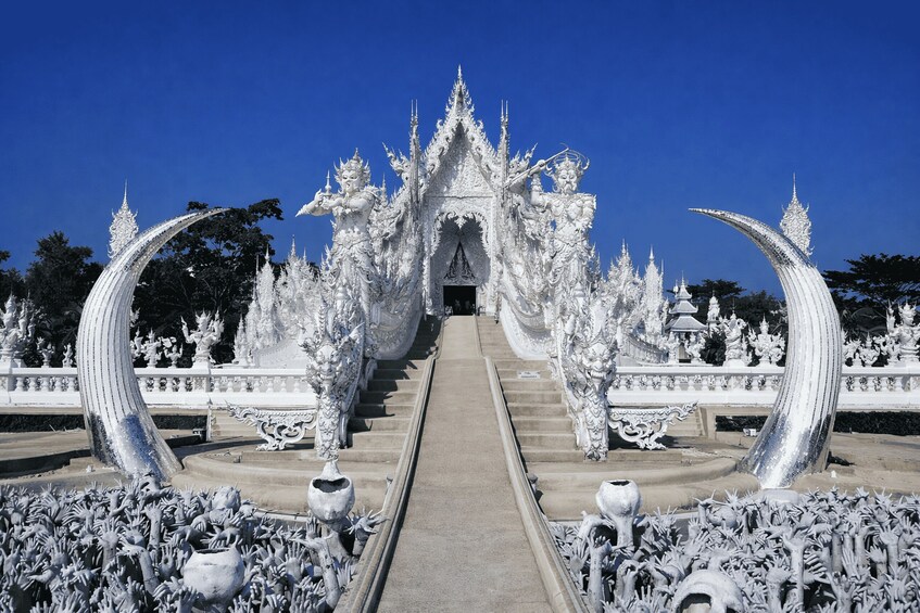 Un temple blanc, richement décoré, avec une entrée centrale flanquée de grandes structures incurvées. 2