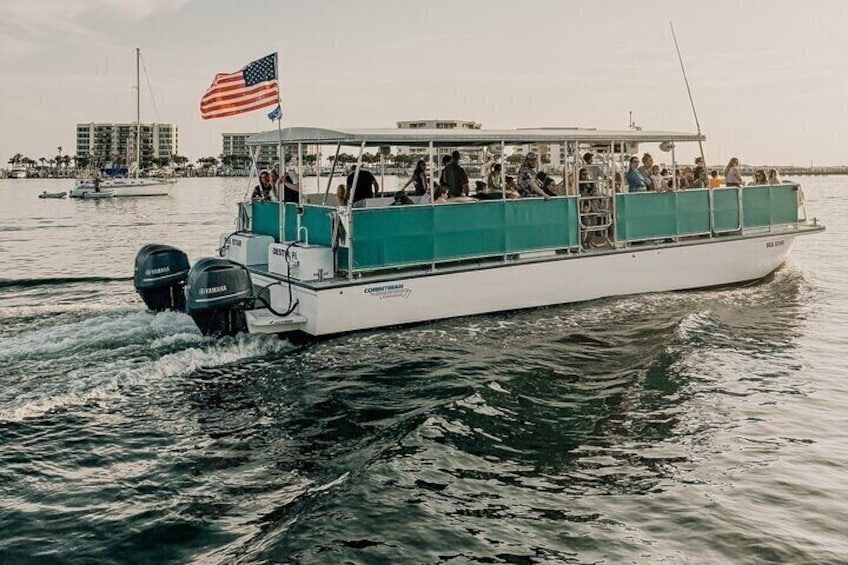 A white boat with an American flag, moving on water with people on board. 4