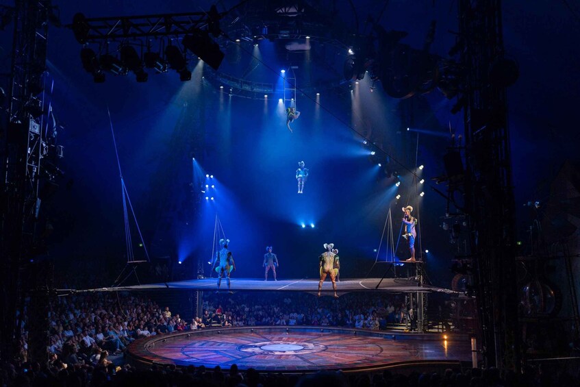 A stage with performers in costumes, a circular platform, and a seated audience. 5