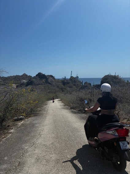 A person riding a motorcycle on a rural road with a clear sky and distant hills. 5