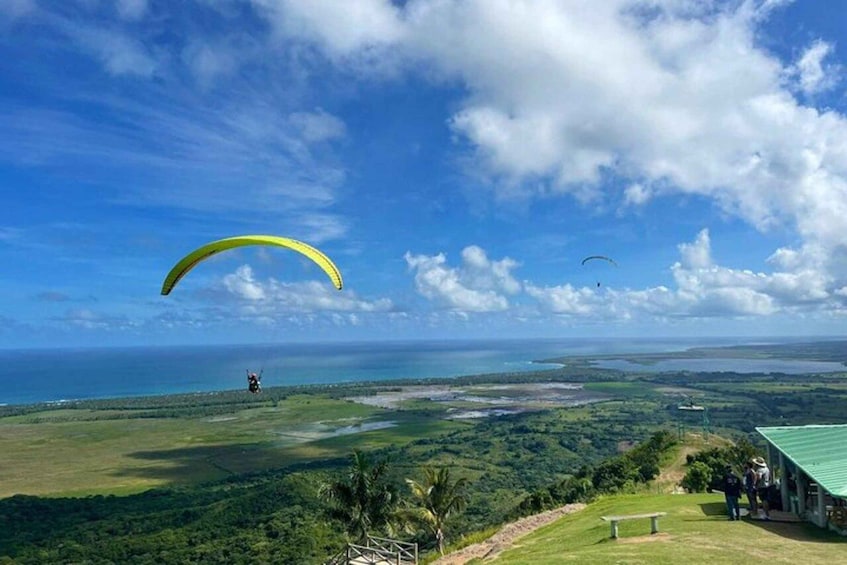 A person paragliding over a coastal landscape with a clear sky and distant horizon. 3