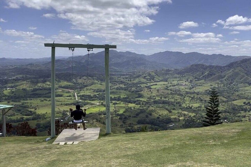A person running on a wooden path with a metal structure overhead, surrounded by a hilly landscape. 2