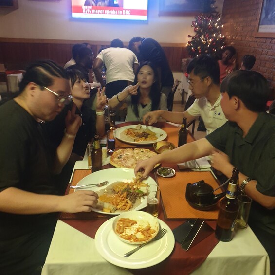 A group of people dining at a restaurant with a Christmas tree in the background. 5