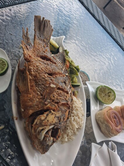 A plate of fried fish, rice, and vegetables on a table. 4