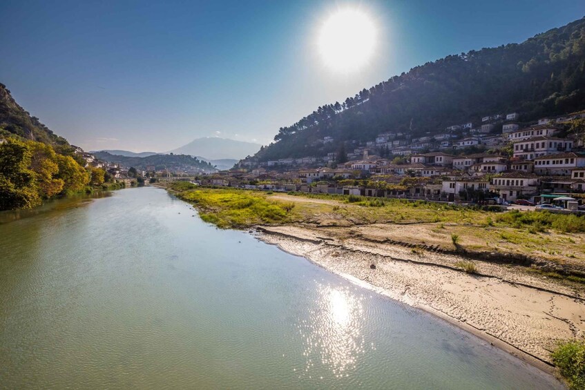 Un río con casas en sus orillas, cielo despejado y un paisaje iluminado por el sol. 4