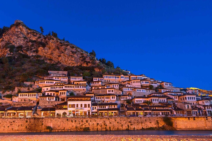 Un pueblo costero con edificios escalonados, una colina destacada y un mar tranquilo. 1